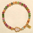 Colorful beaded bracelet with a gold heart charm on a beige background