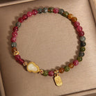 Multicolored beaded bracelet with a gold charm on a beige background