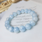 Blue beaded bracelet on a white surface with a gold object in the background