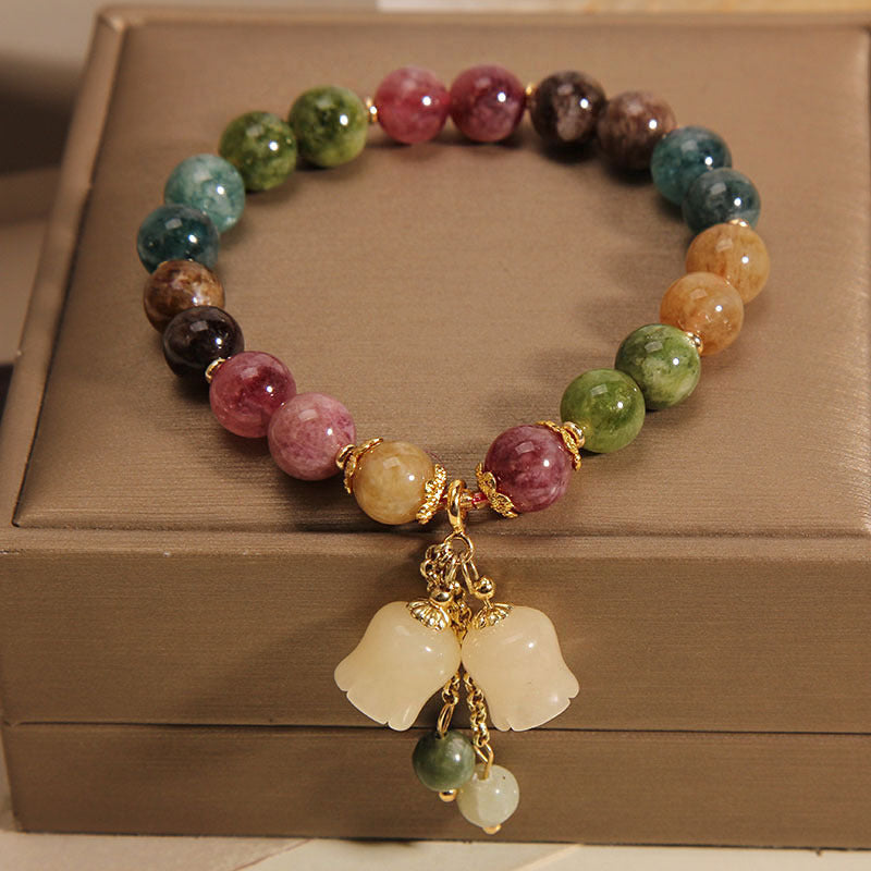 Multicolored beaded bracelet with a gold charm on a brown surface