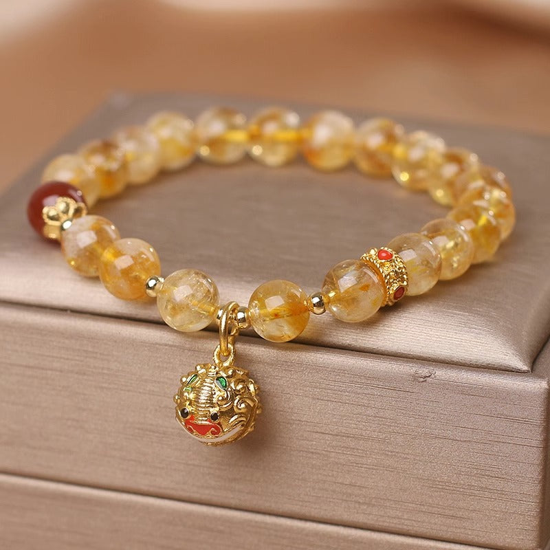 Beaded bracelet with a gold charm on a wooden surface