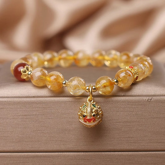 Beaded bracelet with a gold charm on a wooden surface